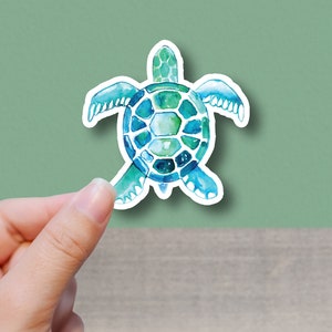 May include: A watercolor sticker of a blue and green sea turtle. The turtle is facing the viewer with its head and legs visible. The sticker has a white border.