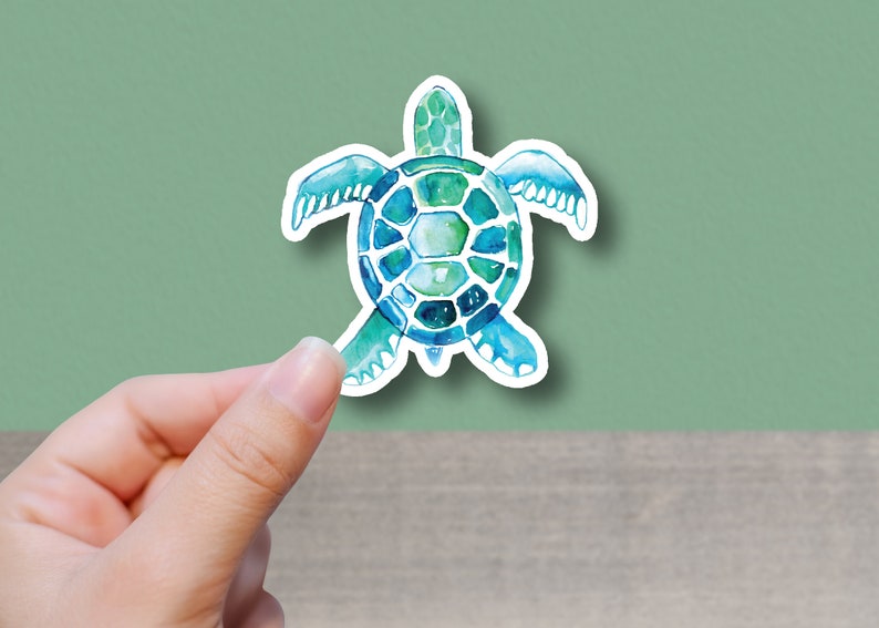 May include: A watercolor sticker of a blue and green sea turtle. The turtle is facing the viewer with its head and legs visible. The sticker has a white border.