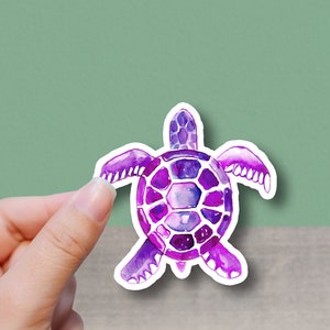 May include: A purple watercolor sea turtle sticker with a white outline. The turtle is facing the viewer with its head and legs visible.