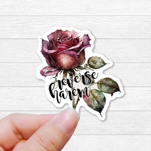 May include: A sticker featuring a watercolor illustration of a single pink rose with green leaves and the text "reverse harem" in black.