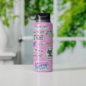 May include: Pink stainless steel water bottle with a black lid and a straw. The bottle is covered in stickers with motivational quotes and images. The text on the bottle reads "Emotional Support Water Bottle", "See the good, your only limit is your mind", "Something today at will improve your tomorrows", "#health", "Boy Mom", "It's fine", "I'm fine, everything is fine", and "It did you die?"