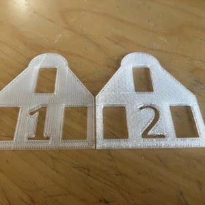 May include: Two white plastic number tags, one with the number "1" and the other with the number "2".