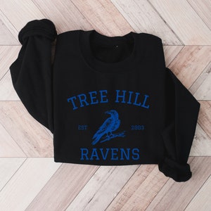 May include: Black sweatshirt with a blue graphic of a raven and the text "Tree Hill Est 2003 Ravens".