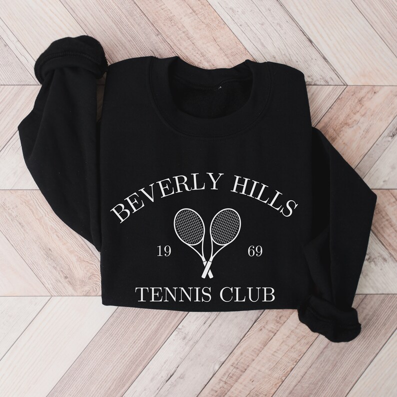 May include: Black sweatshirt with white text that reads "Beverly Hills Tennis Club" with two tennis rackets crossed in the middle and the numbers 19 and 69 on either side.
