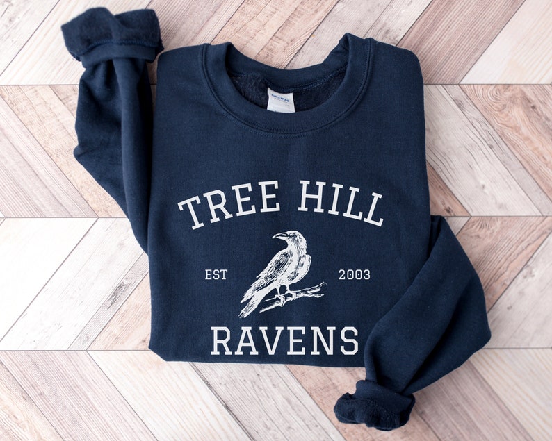 May include: A navy blue sweatshirt with a white graphic of a raven and the text "Tree Hill Est. 2003 Ravens".