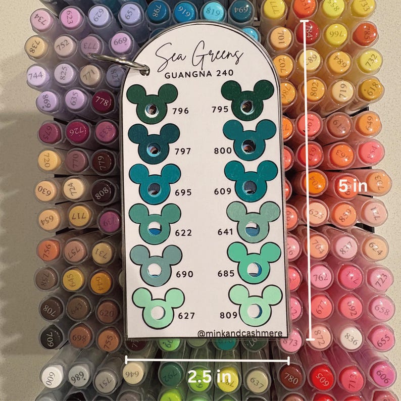 Puede incluir: Una carta de colores etiquetada como "Sea Greens" con una serie de muestras de rotuladores verdes en varios tonos. La carta mide 6,35 cm de ancho y 12,7 cm de alto. Los rotuladores est&aacute;n colocados en un soporte con m&uacute;ltiples colores.