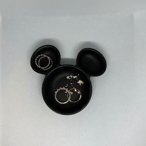 May include: Black ceramic Mickey Mouse-shaped dish with gold rings inside.