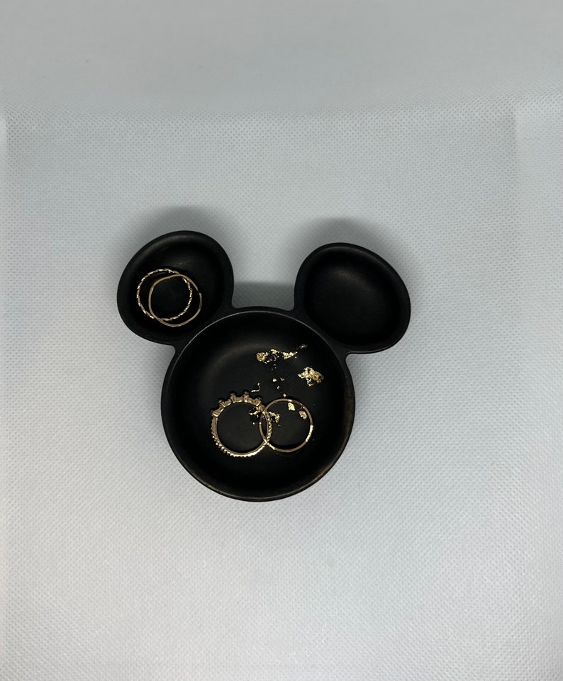 May include: Black ceramic Mickey Mouse-shaped dish with gold rings inside.