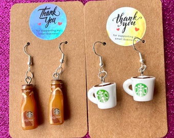 May include: Two pairs of earrings displayed on brown card stock. The earrings are made from polymer clay and feature a coffee bottle and a coffee cup with the Starbucks logo. The card stock has a thank you sticker with the text "Thank You for supporting my small business".