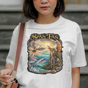 Może przedstawiać: Biała koszulka z kolorową grafiką. Grafika zawiera napis "Span Fan" oraz ilustracje ptaka, smoka i latającej ryby nad zamkiem i morzem.