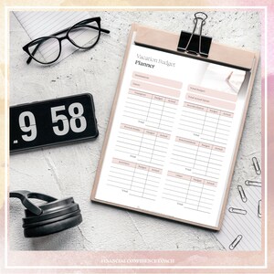 May include: A Vacation Budget Planner sheet on a wooden clipboard with a black clip. The form includes sections for destination, dates, and budget categories like transport, food, accommodation, and activities. Nearby are black glasses and a digital clock.