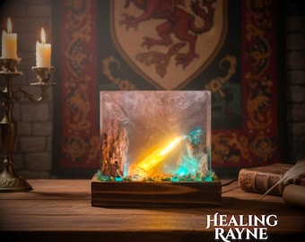 May include: A decorative resin art piece with a wooden base, featuring a fiery dragon design. The artwork showcases a dragon breathing fire, with a mix of yellow, orange, and blue hues. The text "HEALING RAYNE" is visible at the bottom.