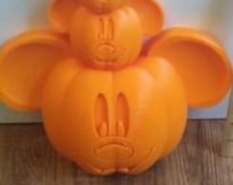 May include: Three stacked orange pumpkins carved with Mickey Mouse faces. The pumpkins are different sizes, with the smallest on top.