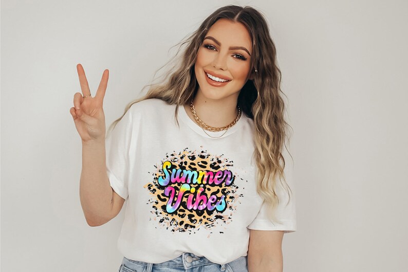 Pu&ograve; includere: T-shirt bianco con grafica colorata "Summer Vibes". Il design presenta uno sfondo con stampa leopardata con le parole in una sfumatura arcobaleno. La maglietta &egrave; uno stile estivo casual.