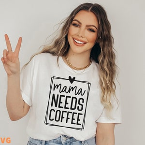 Pode incluir: Camiseta branca com texto preto que diz "mama needs coffee" dentro de um quadro quadrado preto com um pequeno cora&ccedil;&atilde;o preto acima do texto.
