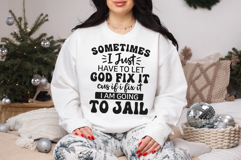 May include: White sweatshirt with a black graphic print that reads "Sometimes I Just Have To Let God Fix It Cus If I Fix It I Am Going To Jail".