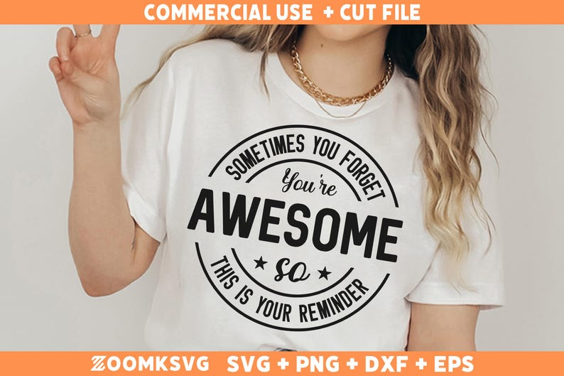 Op de afbeelding: Wit T-shirt met een zwart cirkelvormig ontwerp met de tekst "Soms vergeet je dat je geweldig bent. Dit is je herinnering."
