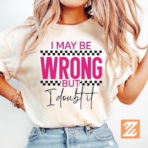 May include: Cream-colored t-shirt with the text "I MAY BE WRONG BUT I doubt it" in black and pink. The text is arranged in a bold, eye-catching design. The shirt has short sleeves and a casual fit.