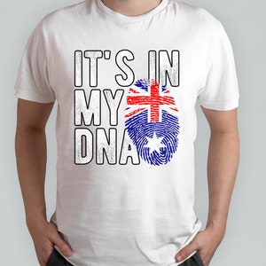 May include: White t-shirt with the text "IT'S IN MY DNA" in a bold, distressed font. The design includes a fingerprint graphic in the colors of the Australian flag. The shirt is a casual wear item.