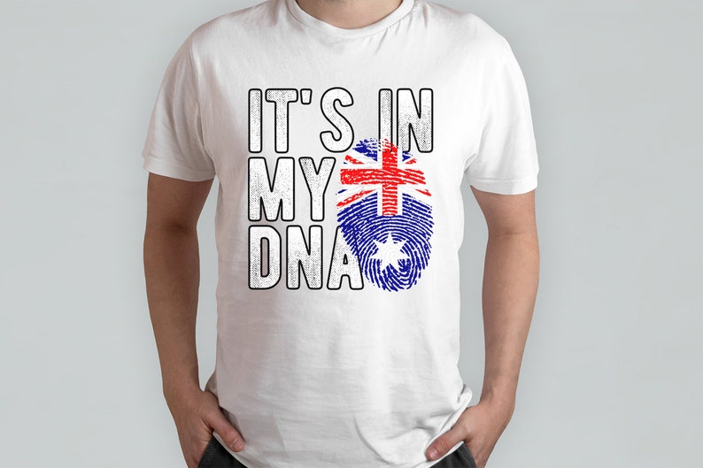 May include: White t-shirt with the text "IT'S IN MY DNA" in a bold, distressed font. The design includes a fingerprint graphic in the colors of the Australian flag. The shirt is a casual wear item.