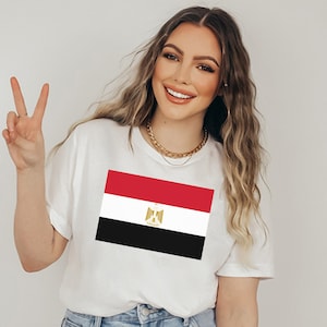 May include: A white t-shirt with a printed image of the Egyptian flag. The flag is red, white, and black with a gold eagle in the center.
