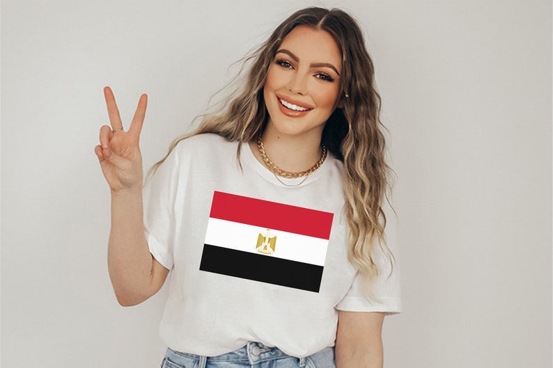 May include: A white t-shirt with a printed image of the Egyptian flag. The flag is red, white, and black with a gold eagle in the center.