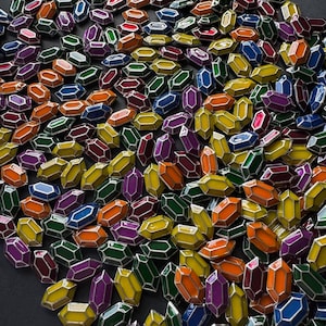 May include: A collection of colourful, faceted glass gems in various shapes and sizes. The gems are arranged in a random pattern, creating a visually appealing display.