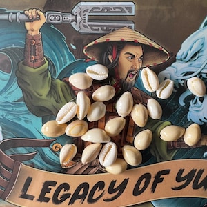 Peut inclure: Une collection de coquillages de cauris blancs sur un fond coloré avec un dessin d'une personne tenant une arme et le texte "Legacy of Yu".