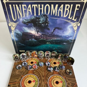 Könnte beinhalten: Ein Brettspiel namens "Unfathomable" mit einer dunkelblauen Schachtel, die ein Monster und ein Schiff zeigt. Das Spiel enthält Charakterkarten mit Illustrationen von Personen und ein Spielbrett mit Zifferblättern.