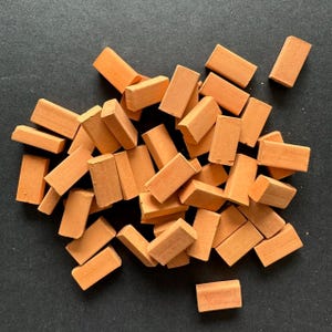 May include: A pile of small, orange-colored brick-shaped craft supplies. The bricks are made of a lightweight material and are perfect for model building or other craft projects.