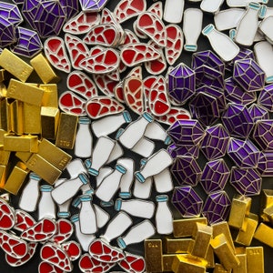 May include: A collection of enamel pins featuring various designs, including milk bottles, geometric shapes, and abstract patterns. The pins are in shades of purple, blue, red, and white.