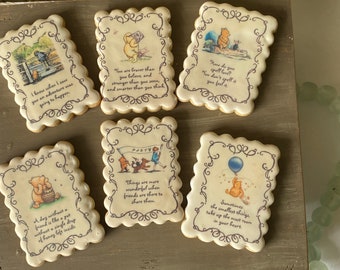 Pode incluir: Seis biscoitos de açúcar decorados com personagens do Winnie the Pooh e citações do livro. Os biscoitos são decorados com glacê marrom e têm uma borda festoneada.