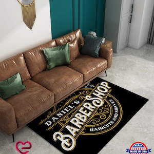 May include: Black and gold barbershop rug with the text "Daniel's Barbershop" and "Haircuts and Shaves" in a vintage style.