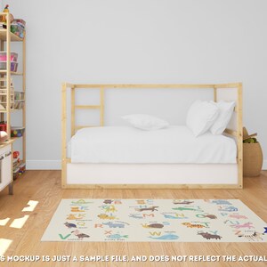 May include: A white and beige alphabet rug with colorful animal illustrations. The rug features the letters A through Z with a corresponding animal for each letter. The rug is laid out on a wooden floor in a room with a white wall, a wooden bed frame, and a wooden shelf.