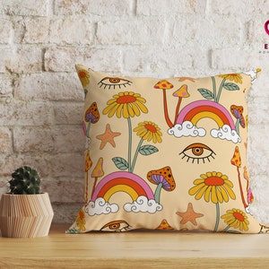 May include: A yellow and orange throw pillow with a psychedelic pattern of rainbows, mushrooms, and eyes. The pillow has a cream background and features the text "Elpis Home Decor".