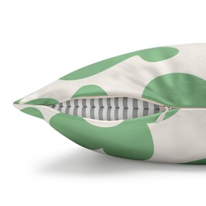 May include: A green and white throw pillow with a zipper closure. The pillow has a pattern of large green circles on a white background.