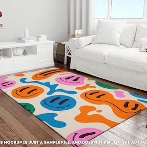 May include: A colorful rug with a white background and a pattern of smiley faces in various colors, including blue, orange, pink, and green. The rug is on a wooden floor in a room with a white couch.