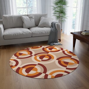 May include: A round area rug with a geometric pattern of overlapping circles in shades of orange, red, and beige. The rug is on a wooden floor in a living room setting.