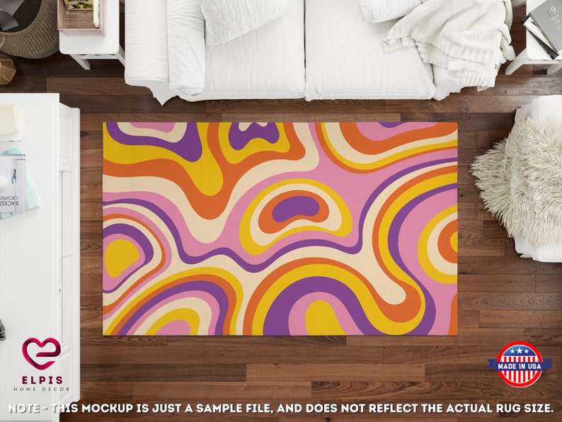 May include: A colorful area rug with a retro design. The rug features a swirling pattern in shades of pink, orange, yellow, purple, and cream. The rug is rectangular and appears to be made of a soft material. The rug is placed on a dark wood floor.