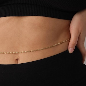 May include: A gold chain body jewelry piece worn around the waist.