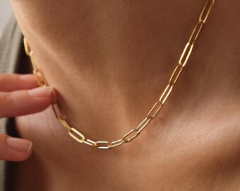May include: A gold chain necklace with a simple, linked design. The chain is made of small, rectangular links.