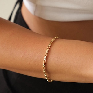 May include: A gold chain bracelet with a simple, boxy link design.