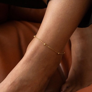 May include: A gold anklet with small round beads on a delicate chain.