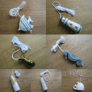 May include: Assortment of ceramic light pull chains with various nautical themes.  The pulls include a fish, a lighthouse, a seahorse, a pineapple, a patterned cylinder, and a whale.
