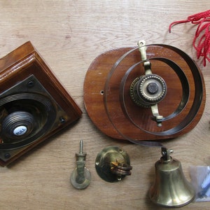 May include: A vintage doorbell kit with a wooden base, a brass bell, a pull button, and a red cord. The kit includes all the necessary hardware for installation.