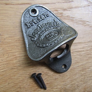 Puede incluir: Un abridor de botellas de hierro fundido con el logotipo de Jack Daniel's. El abridor tiene forma de lágrima y tiene un agujero para colgar. El logotipo dice "Est. 1875 Jack Daniel's Tennessee Whiskey".