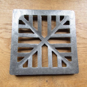 Könnte beinhalten: Ein quadratisches Gitter aus silbernem Metall mit einem dekorativen geometrischen Muster. Das Gitter hat ein Sternmuster mit einem zentralen Kreuz.
