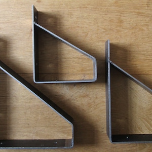 Puede incluir: Tres soportes de estante de metal en diferentes tamaños. Los soportes son de metal negro y tienen forma triangular. Están diseñados para soportar estantes.
