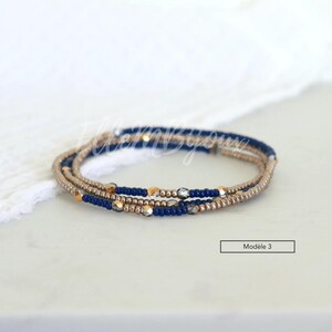 May include: A multi-strand bracelet with blue, gold, and silver beads. The bracelet is on a white surface.  Mod&egrave;le 3