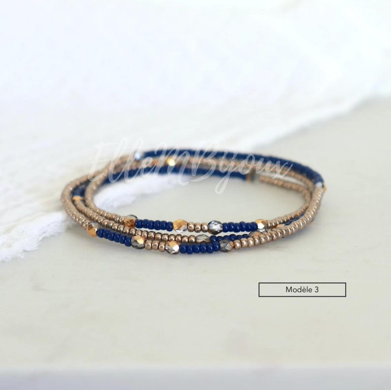 May include: A multi-strand bracelet with blue, gold, and silver beads. The bracelet is on a white surface.  Mod&egrave;le 3